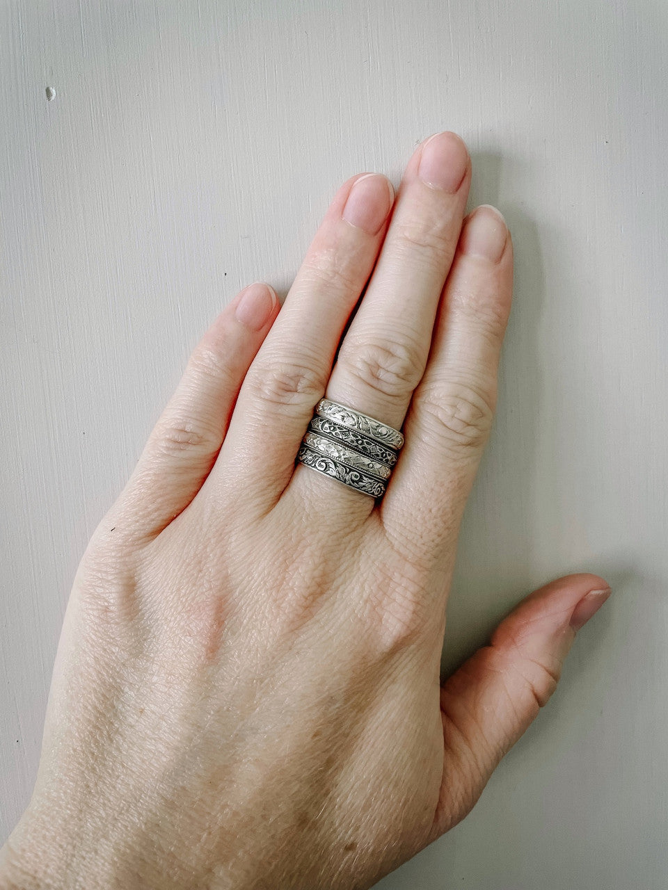 Four different stacking rings on middle finger. Mix and match different styles and finishes.