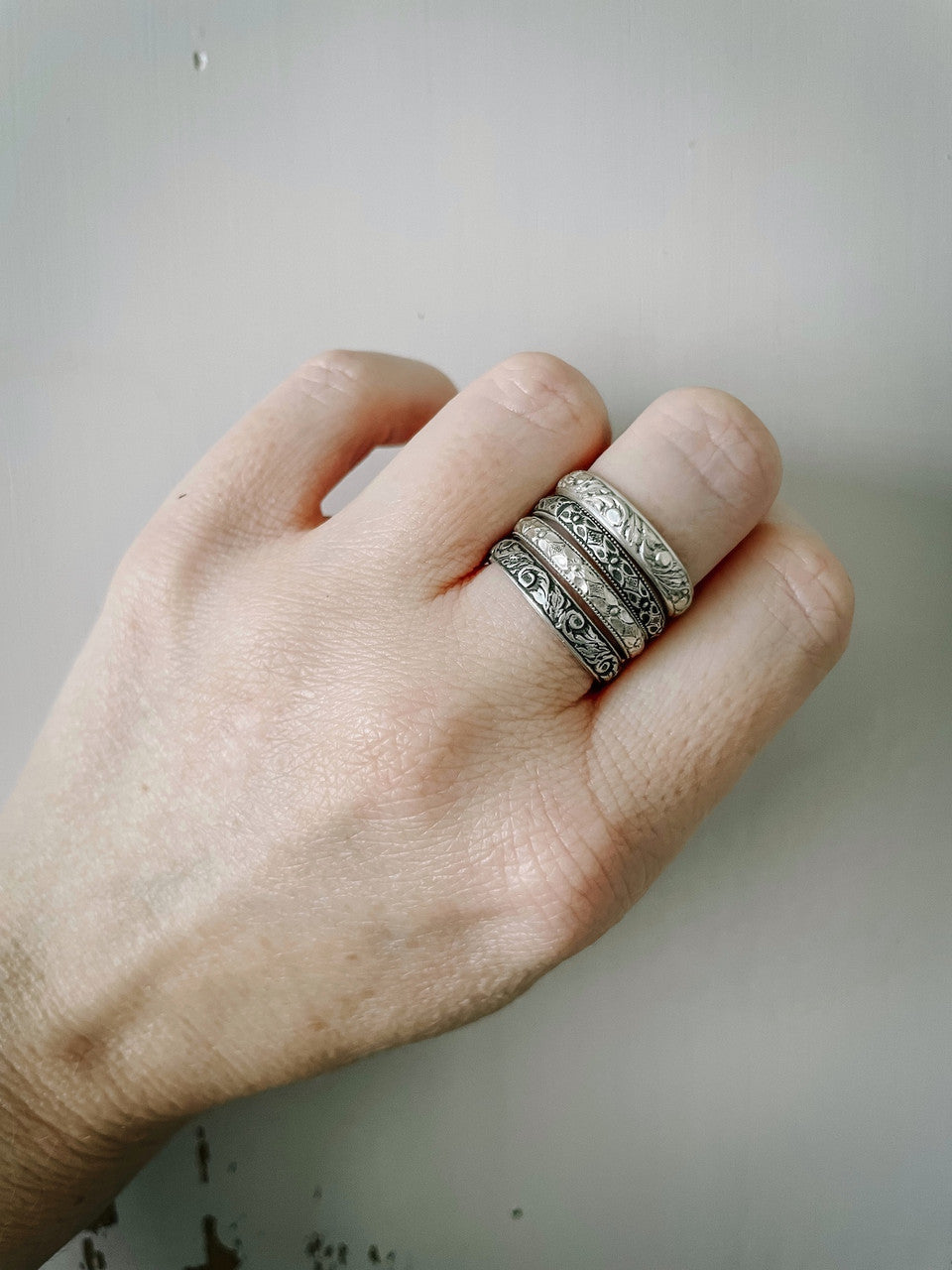 Four different stacking rings on middle finger. Mix and match different styles and finishes.