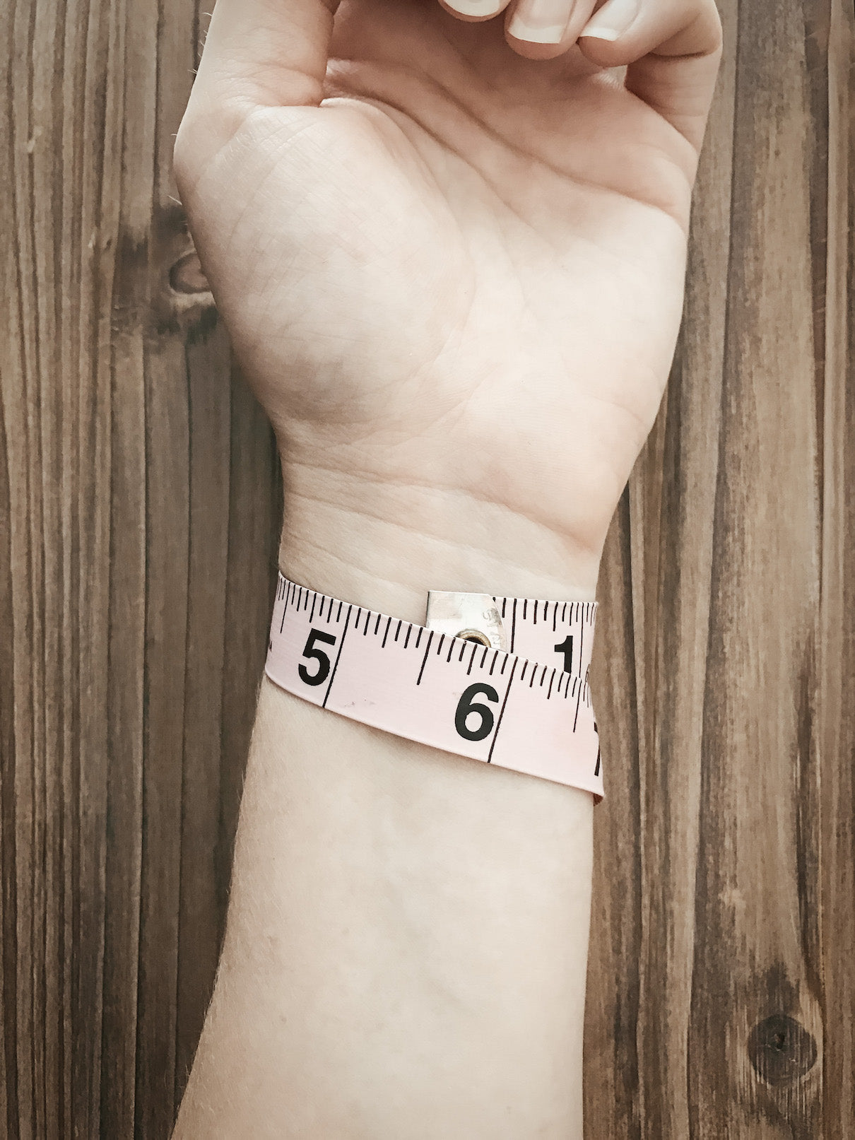 Tape measure wrapped around wrist showing 5.5" measurement
