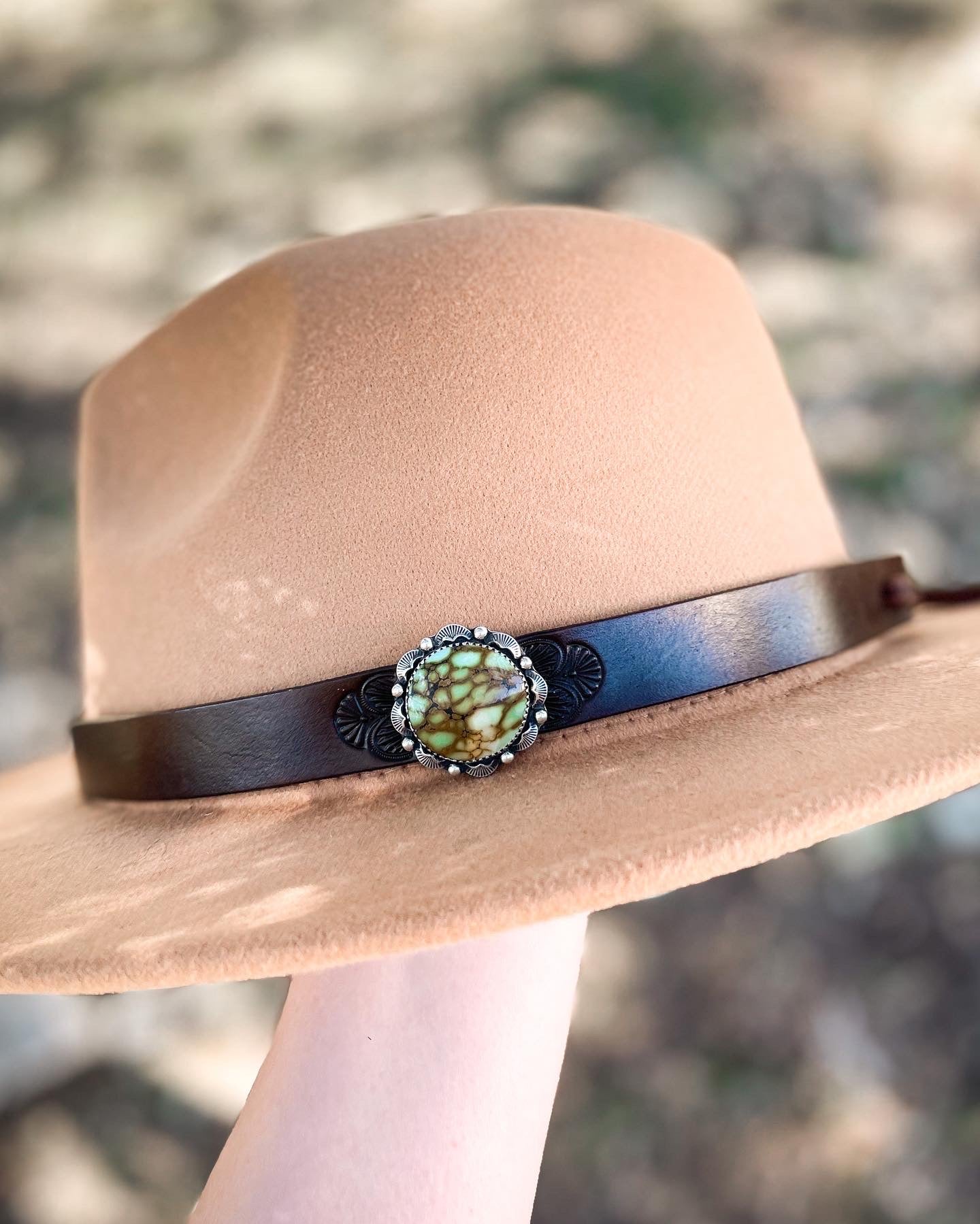 Tan hat with dark leather hatband with stamped design featuring round turquoise hat pin set in sterling silver.