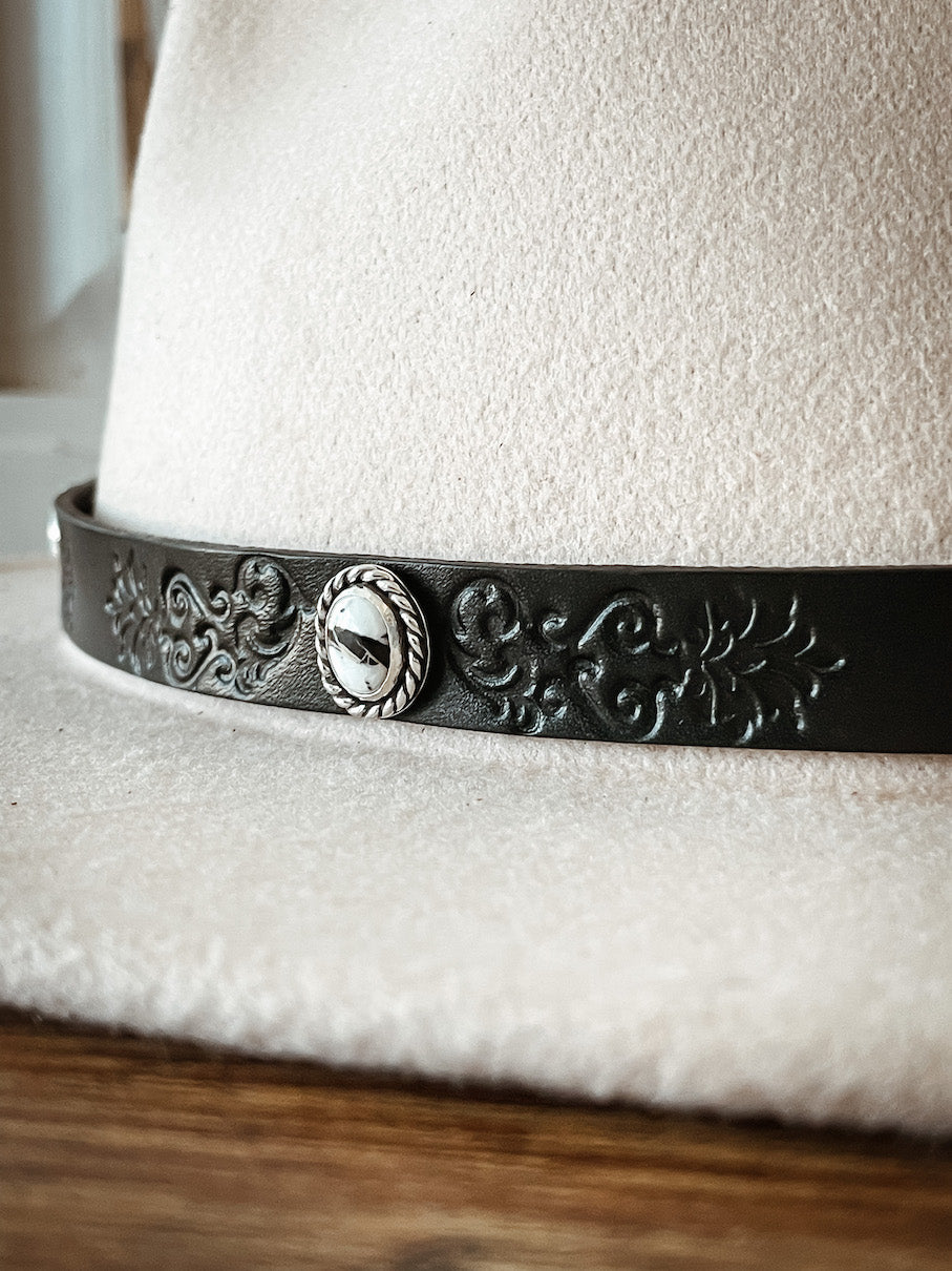 Cream colored hat with dark leather hatband with stamped design featuring round white buffalo stones set in sterling silver.