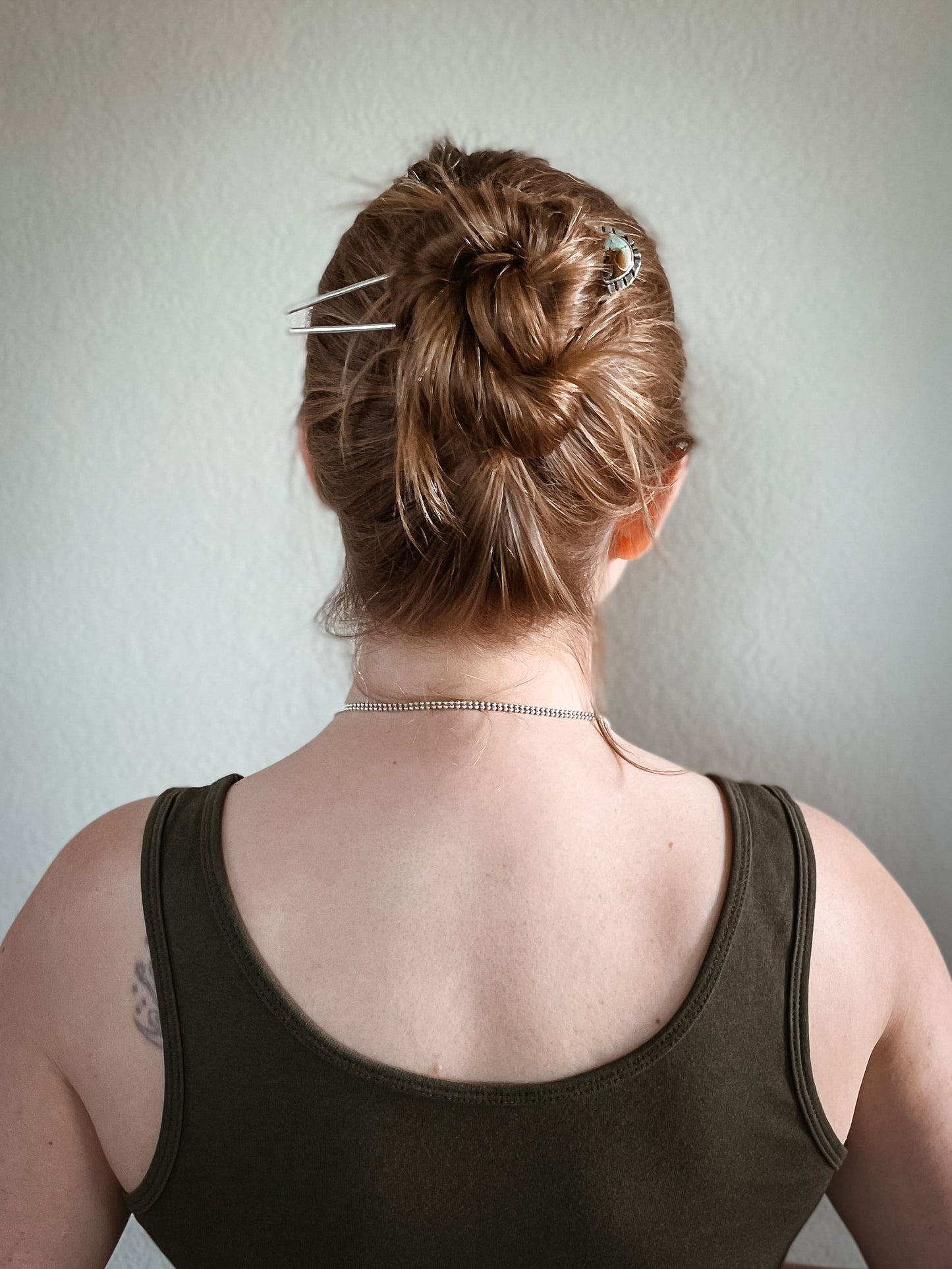 Woman wearing half moon turquoise hair fork in hair securing bun.